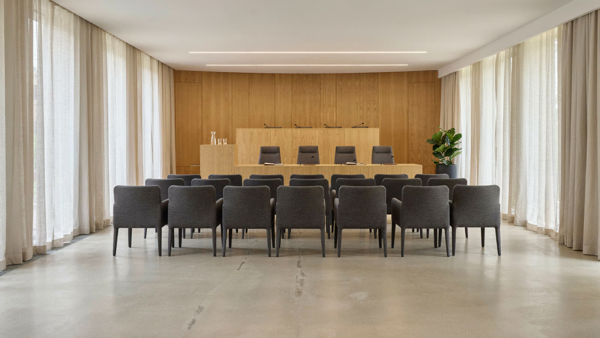 A municipal council chamber with a wood dais and rows of chairs