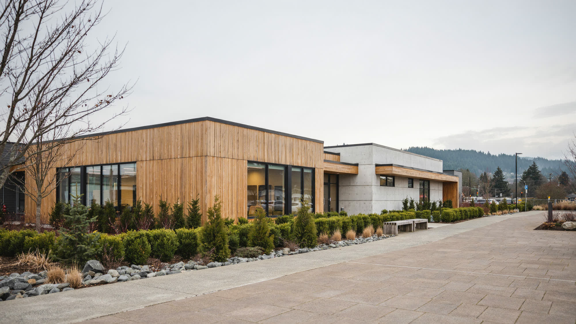 A low timber-and-concrete commercial building with landscaped grounds