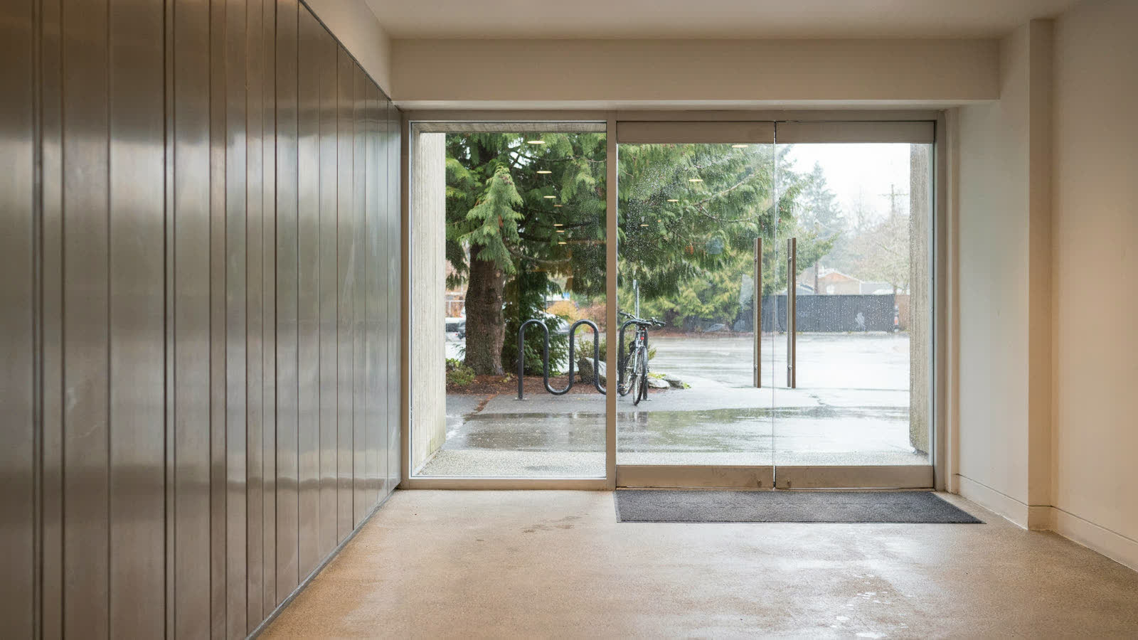 A building entrance vestibule with glass doors on a rainy morning