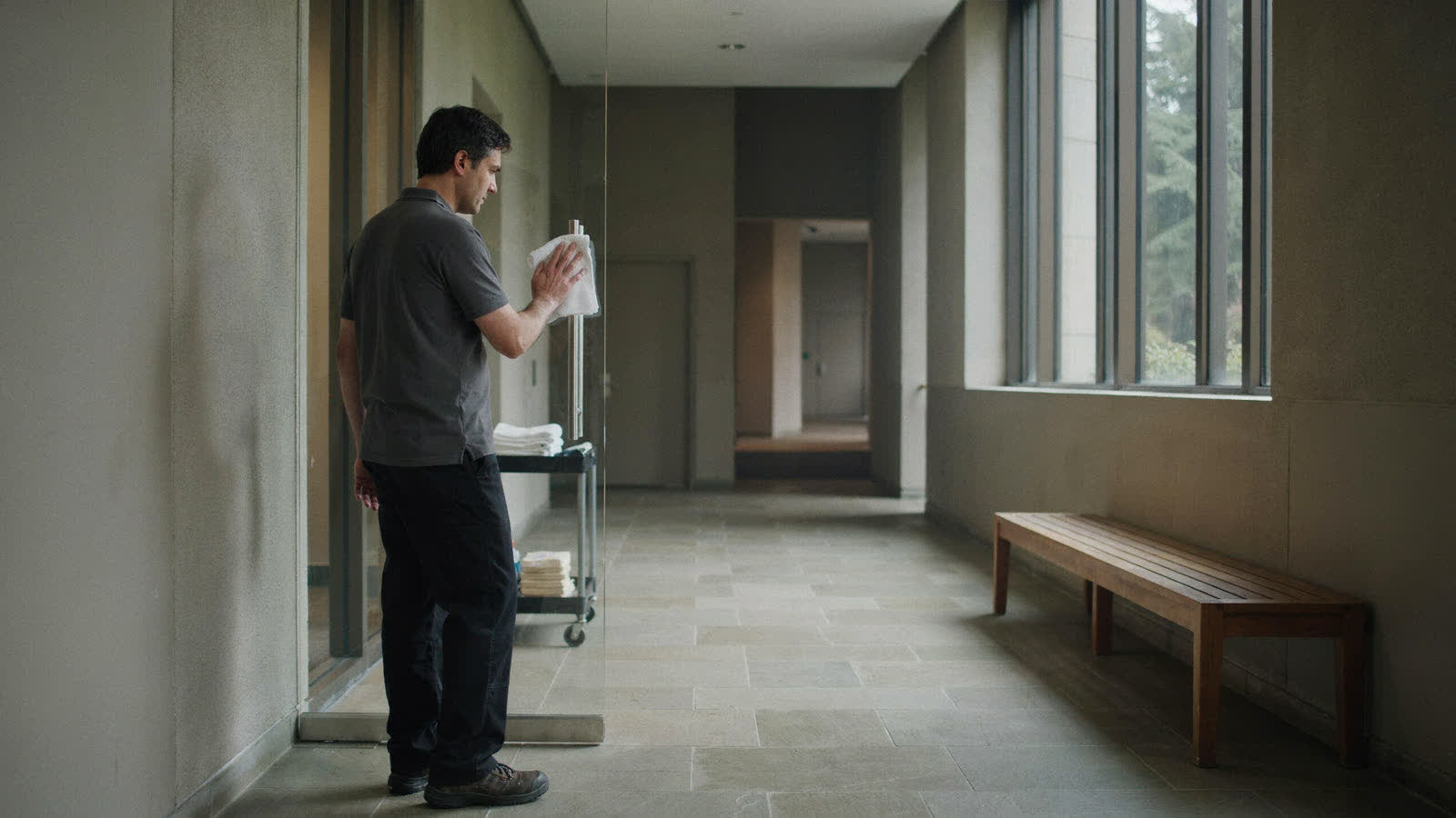 A team member spot-cleaning a glass door in a quiet city hall corridor