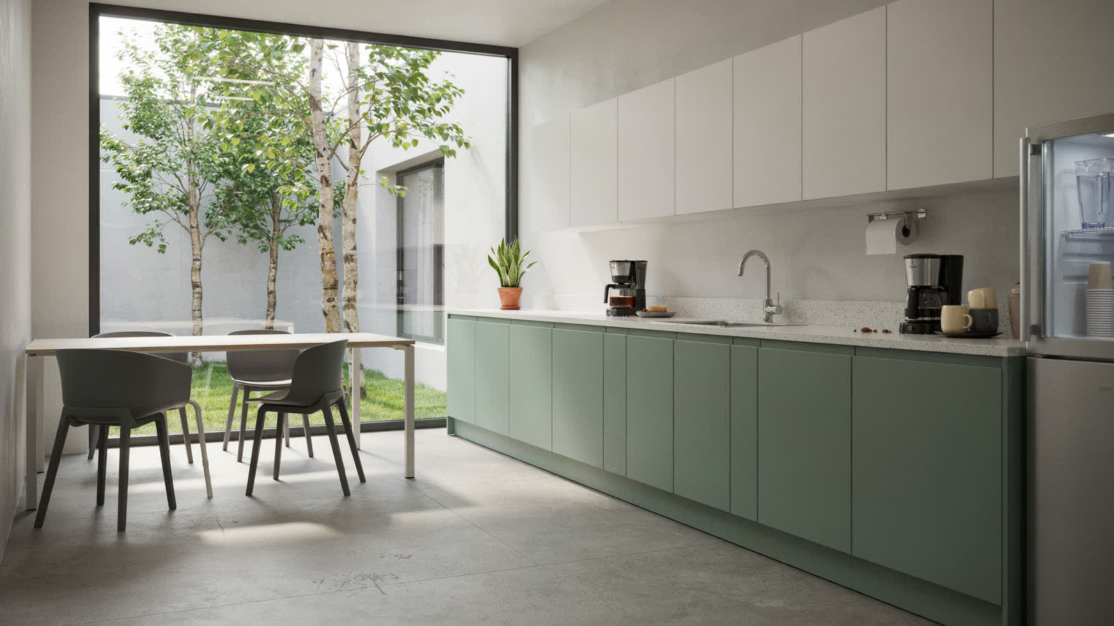 An office break room with sage-green cabinets and a courtyard window